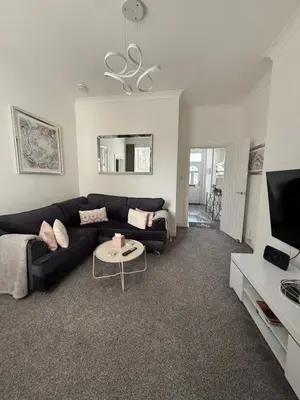 a living room with a black couch and a tv at Cosy Cottage in Stirling