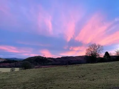 a sunset in a field with a colorful sky at Spacious lodge with king sized bed in Inveraray