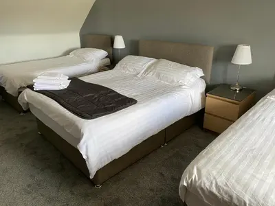 two beds in a hotel room with white sheets at The Barn Lodge in Stirling