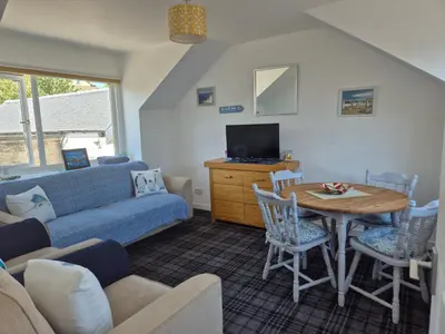 a living room with a couch and a table at Coorie Braw Cottage in Kirn