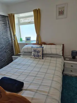 a bedroom with a large bed with a window at Coorie Braw Cottage in Kirn