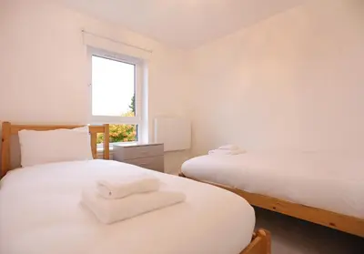 two beds in a room with two white towels on them at The South Maybury Residence in Edinburgh