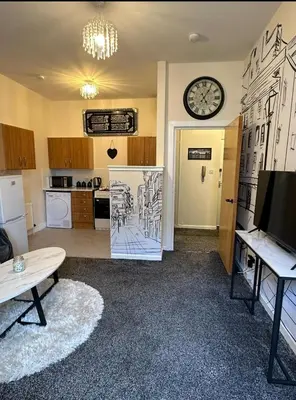 a living room with a clock on the wall at Central Glasgow Apt - Sleeps 2 & FreeParking During Weekend in Glasgow