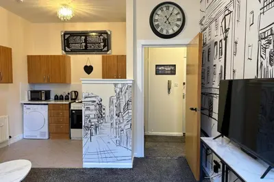a kitchen with a drawing on the wall and a clock at Central Glasgow Apt - Sleeps 2 & FreeParking During Weekend in Glasgow