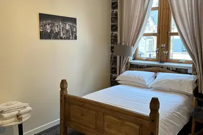 a bedroom with a wooden bed with a window at Central Glasgow Apt - Sleeps 2 & FreeParking During Weekend in Glasgow