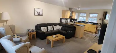 a living room with a couch and a kitchen at The Cobbler Cottage - Loch Lomond and Arrochar Alps in Arrochar