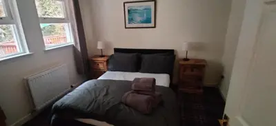 a bedroom with a bed and two windows at The Cobbler Cottage - Loch Lomond and Arrochar Alps in Arrochar