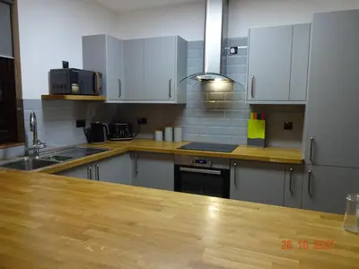 a kitchen with white cabinets and a wooden counter top at The Stables near Glasgow in Balmore