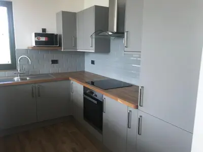 a kitchen with white cabinets and a wooden counter top at The Stables near Glasgow in Balmore