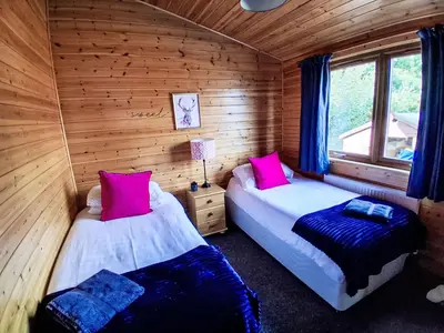 two beds in a room with wooden walls at Chalet Loch Leven Lodge 12 by Interhome in Kinross