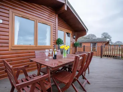 a wooden table and chairs on a deck at Chalet Loch Leven Lodge 12 by Interhome in Kinross