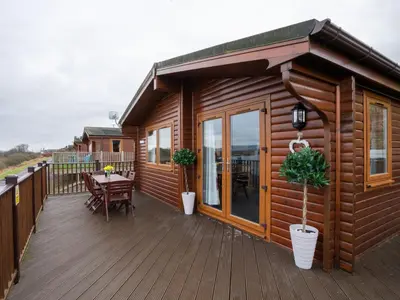 a wooden cabin with a table on a deck at Chalet Loch Leven Lodge 12 by Interhome in Kinross