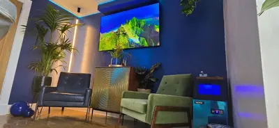 a living room with three chairs and a tv on a blue wall at The NEW Blue Horse Suite at The Grumpy Schnauzer B&B Luxury Private Indoor Hot Tub Breakfast in Bed in Airdrie