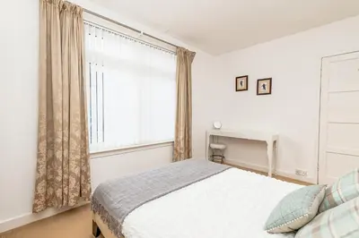a bedroom with a bed and a large window at Balmoral Residence 30 mins from Edinburgh and Glasgow in Falkirk