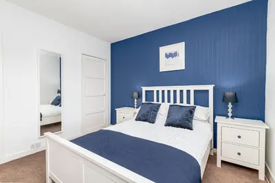 a blue bedroom with a white bed and blue wall at Balmoral Residence 30 mins from Edinburgh and Glasgow in Falkirk