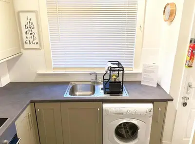 a kitchen with a sink and a washing machine at Balmoral Residence 30 mins from Edinburgh and Glasgow in Falkirk