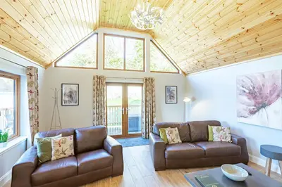 a living room with two couches and a table at Kestrel Lodge 6 with Hot Tub in Newton Stewart