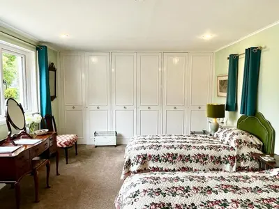 a bedroom with two beds and a dresser and a desk at Whitehouse in Uplawmoor