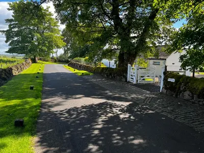 a road with a fence and a house and trees at Whitehouse in Uplawmoor