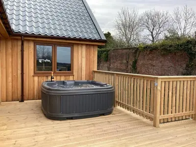 a hot tub sitting on a deck next to a house at Osprey Lodge 8 with Hot Tub in Newton Stewart