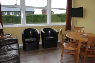 a living room with a table and two black chairs and a table and two chairs at The Old School in Dalavich