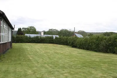 a large yard next to a building with bushes at The Old School in Dalavich