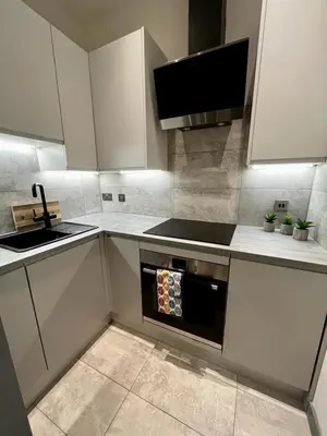 a kitchen with white cabinets and a sink and an oven at 1 bed Apt in West End in Glasgow
