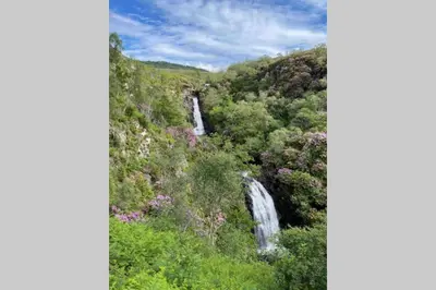 a waterfall on the side of a hill with trees at Sea Breeze Pod in Fort William