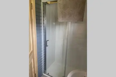 a shower with a glass door next to a toilet at Sea Breeze Pod in Fort William
