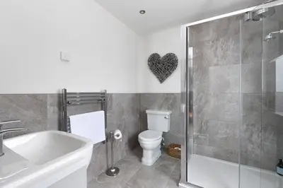 a bathroom with a toilet and a glass shower at Slatehouse Cottage, Drumlanrig in Thornhill