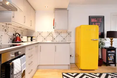 a yellow refrigerator in a kitchen with white cabinets at JOIVY Charming Home with Patio Nearby the Castle in Edinburgh
