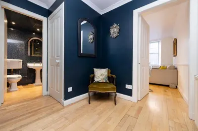 a blue bathroom with a chair and a mirror at JOIVY Charming Home with Patio Nearby the Castle in Edinburgh
