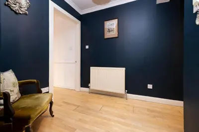 a living room with a blue wall and a radiator at JOIVY Charming Home with Patio Nearby the Castle in Edinburgh
