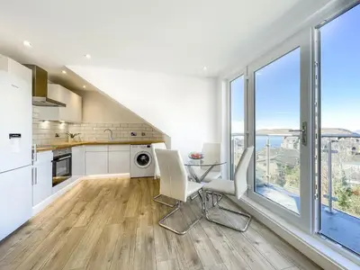 a kitchen with a table and chairs and windows at The Penthouse in Oban