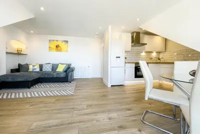 a living room with a couch and a kitchen at The Penthouse in Oban