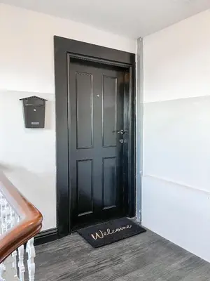 a black door with a welcome mat in front of it at The Penthouse in Oban