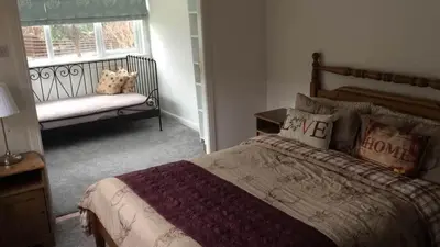 a bedroom with a bed and a bench and a window at Kilburn Holiday Cottage in Largs