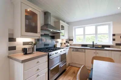 a kitchen with white cabinets and a stove top oven at Kilburn Holiday Cottage in Largs