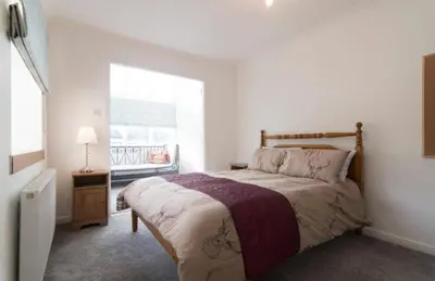 a bedroom with a large bed and a window at Kilburn Holiday Cottage in Largs