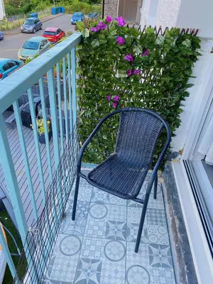 a black chair sitting on a balcony with flowers at Entire Modern Apartment in Oban with Balcony in Oban