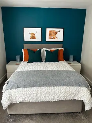a bedroom with a large bed with a blue wall at Entire Modern Apartment in Oban with Balcony in Oban