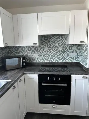 a kitchen with white cabinets and a black oven at Entire Modern Apartment in Oban with Balcony in Oban