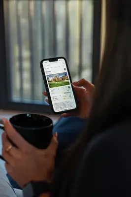 a woman holding a cell phone and a cup of coffee at City View - A Stunning 2 Bed Apartment in Glasgow