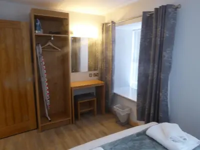 a bedroom with a bed and a desk and a mirror at Auchendennan Farm Self Catering Cottages in Balloch