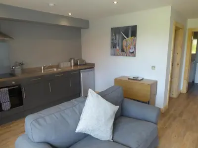 a living room with a couch and a kitchen at Auchendennan Farm Self Catering Cottages in Balloch