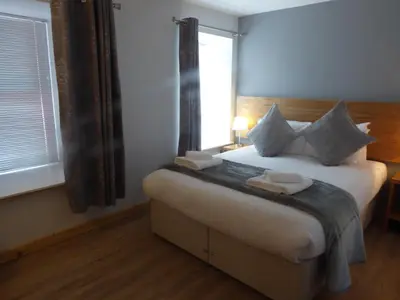 a bedroom with a large bed with a window at Auchendennan Farm Self Catering Cottages in Balloch