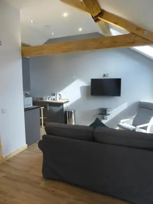 a living room with a couch and a tv on the wall at Auchendennan Farm Self Catering Cottages in Balloch