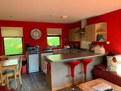 a kitchen with red walls and a counter with red stools at Snowberry Cottages No1 in Onich