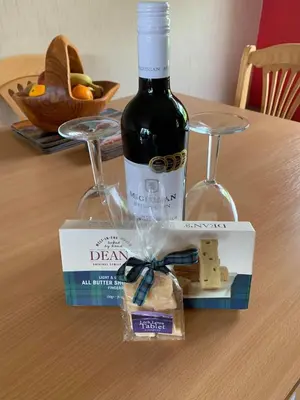 a bottle of wine on a table with a box of cheese at Snowberry Cottages No1 in Onich
