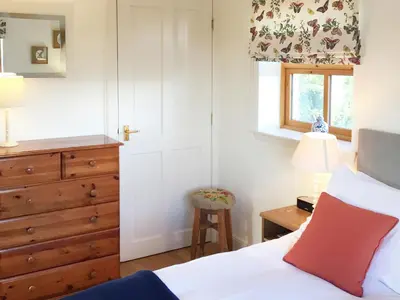 a bedroom with a bed and a dresser and a window at The Wee House in Muthill